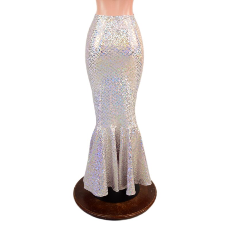 May include: A floor-length, high-waisted skirt featuring a shimmering, iridescent silver finish with a repeating scale-like pattern. The garment has a fitted silhouette through the hips and thighs, flaring out into a wide, ruffled mermaid hem.