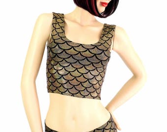 Puede incluir: Un conjunto de dos piezas con un top corto y unos shorts. El conjunto está adornado con un estampado de escamas doradas y negras. El top tiene un escote redondo y los shorts son de cintura baja. El conjunto se exhibe en un maniquí.
