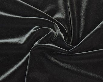 May include: Black velvet fabric with a soft, smooth texture. The fabric is draped and folded, showcasing its luxurious feel.