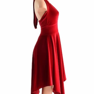 May include: A red velvet halter dress with a high neckline and a flowing skirt. The skirt is asymmetrical, with one side longer than the other.