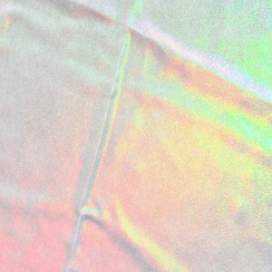 May include: A close-up of iridescent fabric with a subtle rainbow sheen. The fabric is folded and has a textured surface.