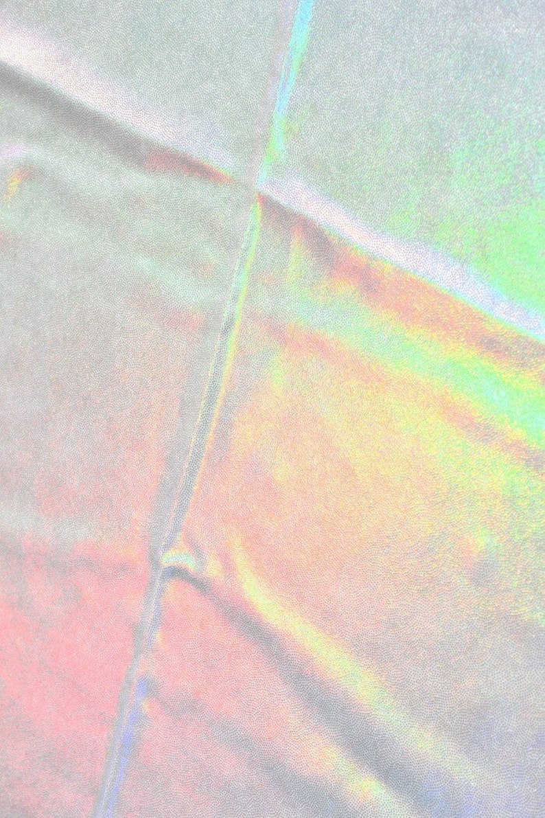 May include: A close-up of iridescent fabric with a subtle rainbow sheen. The fabric is folded and has a textured surface.