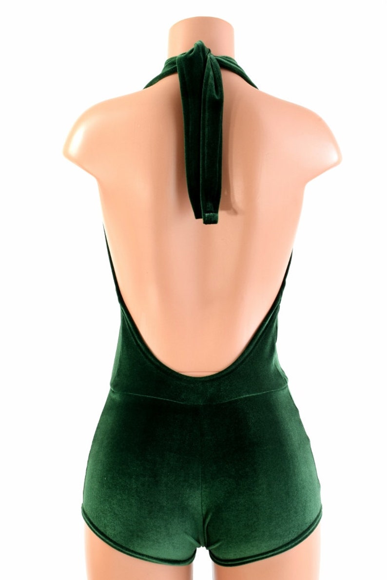 May include: A halter-style bodysuit with a deep V-back, made of a dark green velvet fabric. The bodysuit has a tie at the neck and short shorts.