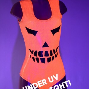 May include: Orange sleeveless bodysuit with a black jack-o'-lantern design. The text "UNDER UV BLACKLIGHT!" is printed on the bottom of the bodysuit.