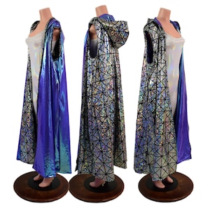 May include: A hooded cape with a geometric pattern in silver and black, paired with a vibrant blue iridescent lining. The cape is displayed on a mannequin, showcasing its flowing design. The garment is a striking piece of apparel.