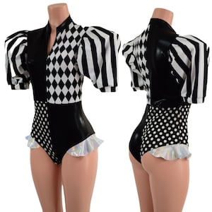 May include: Black and white bodysuit with a harlequin pattern on the top and polka dots on the bottom. The bodysuit has a high collar and short sleeves with a ruffle trim. The sleeves are striped black and white.