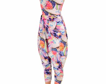 May include: A colorful jumpsuit with a white background and a variety of abstract shapes and patterns in pink, blue, green, and purple. The jumpsuit has a sleeveless design and a wide leg.