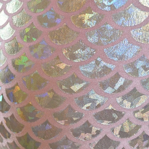Pu&ograve; includere: Primo piano di un tessuto rosa con un motivo a squame di sirena olografico. Le squame sono iridescenti e brillano alla luce.