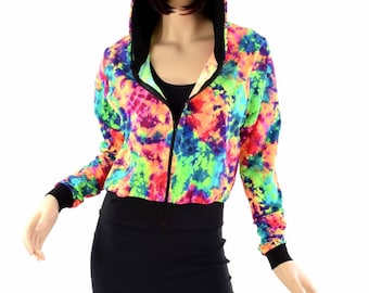 May include: A vibrant, tie-dye hooded jacket with a black zipper, cuffs, and hood lining. The jacket features a colorful pattern of neon green, blue, orange, and purple. The model is also wearing a black skirt.