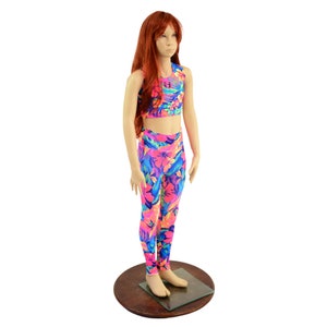 May include: A two-piece outfit for girls featuring a pink crop top and matching leggings. The fabric has a bright, colorful tropical print with pink, blue, yellow, and green hues.