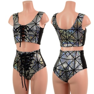 May include: A two-piece outfit with a geometric design. The top and high-waisted bottoms are silver with black geometric lines and black side panels. The top and bottoms have a lace-up front.