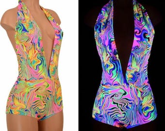 May include: A sleeveless bodysuit featuring a deep V-neckline and a halter-style neck strap. The garment displays a vibrant, multi-colored marbled pattern in neon pink, yellow, green, and blue hues, shown in both daylight and a glowing dark environment.