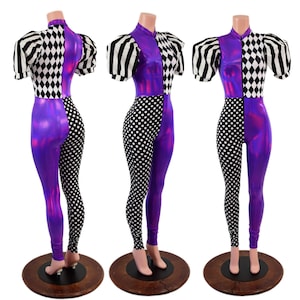 May include: A three-panel display of a purple, black, and white jumpsuit. The jumpsuit features a high collar, puff sleeves, and a split design with harlequin, polka dot, and striped patterns. The shiny purple fabric contrasts with the black and white patterns.