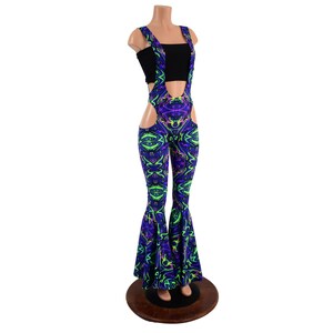 May include: Purple and green patterned bell bottom pants with a cutout on the side and suspenders. The pants are on a mannequin.