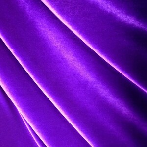 May include: Close-up of a smooth, rich purple velvet fabric with soft folds and a subtle sheen.