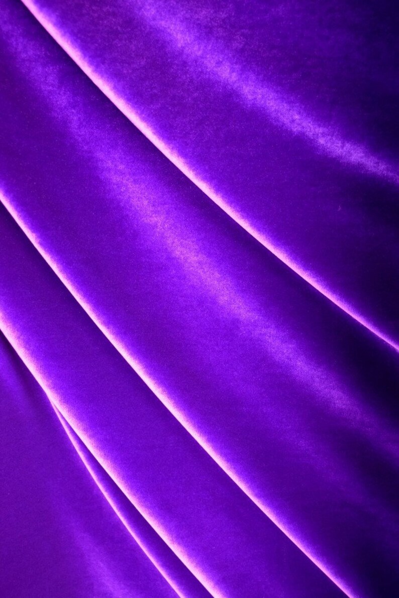 May include: Close-up of a smooth, rich purple velvet fabric with soft folds and a subtle sheen.