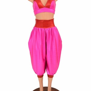 May include: A two-piece outfit with a red and pink color scheme. The top is a cropped halter style with a V-neckline. The pants are high-waisted and have a wide leg, with a gathered look at the waist. The outfit is made of a shiny, stretchy fabric.