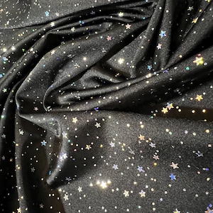 May include: Black fabric with a shimmering, star-like pattern. The fabric is draped, creating folds and shadows. The stars are in various sizes and colors, adding a celestial effect. The fabric appears to be soft and flowing, suitable for apparel or decorative projects.