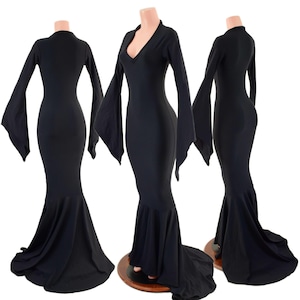 May include: Three black, floor-length dresses on mannequins. Each dress features long, flared sleeves and a mermaid-style skirt. One dress has a V-neck, while the others have a high neckline. The dresses are displayed on wooden stands.