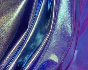 May include: Close-up of iridescent fabric with a blue, purple, and green color scheme. The fabric is smooth and shiny, with a slight sheen.