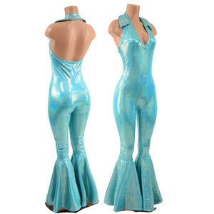 May include: A light blue holographic jumpsuit featuring a halter neckline with a collar, a sleeveless bodice, and flared pant legs. The fabric has a reflective, shimmering finish that catches the light, creating a metallic appearance throughout.