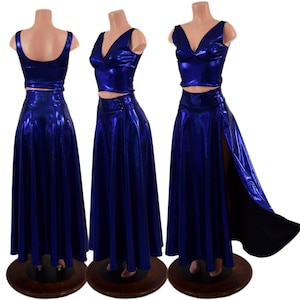 May include: Three-piece set in a vibrant blue metallic fabric. The set includes a crop top and a high-waisted, floor-length skirt. One skirt has a high slit. The outfits are displayed on mannequins with wooden bases.