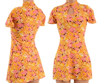 May include: A short, yellow dress with a pink and orange floral print. The dress has a high neck and short sleeves. It has a keyhole cutout at the neckline.