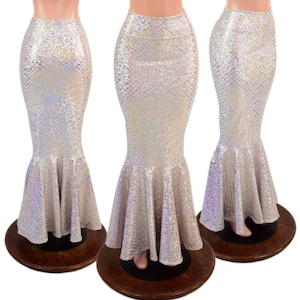 May include: A floor-length mermaid skirt featuring a high-waisted design and a flared hem. The fabric is white with a holographic, iridescent scale pattern that reflects light, creating a shimmering effect across the entire surface of the garment.