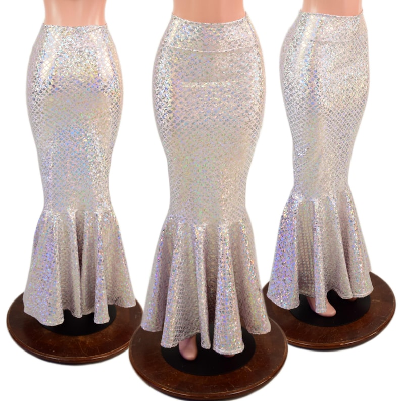 May include: A floor-length mermaid skirt featuring a high-waisted design and a flared hem. The fabric is white with a holographic, iridescent scale pattern that reflects light, creating a shimmering effect across the entire surface of the garment.