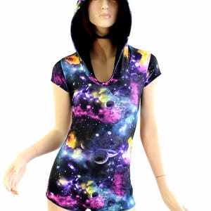 May include: A hooded romper featuring a vibrant galaxy print in shades of purple, blue, yellow, and pink. The short-sleeved garment has a scoop neckline and attached hood. The fabric appears to be a soft, stretchy material.