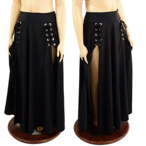 May include: Black maxi skirt with high side slits and lace-up detailing. The skirt features grommets and a flowing design, offering a dramatic and versatile look. The skirt is displayed on a mannequin.