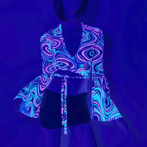 May include: A neon pink, blue, and purple swirl pattern crop top with long sleeves and a tie at the waist. The top is made of a stretchy, comfortable fabric.