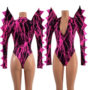 May include: A black and pink long-sleeved bodysuit with a lightning bolt pattern. The bodysuit has a V-neck and a high-cut leg. The sleeves have pink spikes.