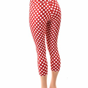 May include: Red and white polka dot leggings with a high waist. The leggings are cropped and the model is wearing them with a white background.