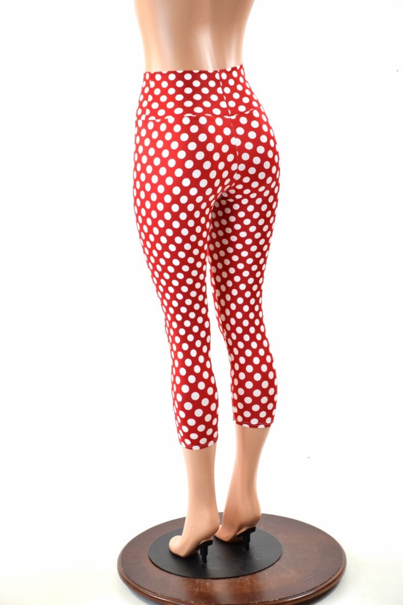 May include: Red and white polka dot leggings with a high waist. The leggings are cropped and the model is wearing them with a white background.
