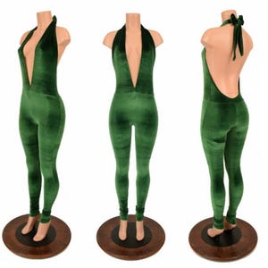 May include: A green velvet jumpsuit with a plunging neckline and halter tie. The jumpsuit is displayed on a mannequin, showcasing the front, side, and back views. The fabric has a soft, textured appearance.