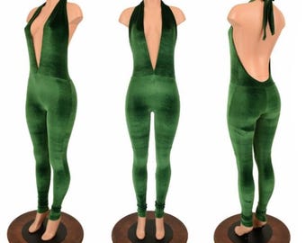 May include: A green velvet jumpsuit with a plunging neckline and halter tie. The jumpsuit is displayed on a mannequin, showcasing the front, side, and back views. The fabric has a soft, textured appearance.