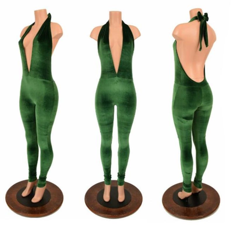 May include: A green velvet jumpsuit with a plunging neckline and halter tie. The jumpsuit is displayed on a mannequin, showcasing the front, side, and back views. The fabric has a soft, textured appearance.