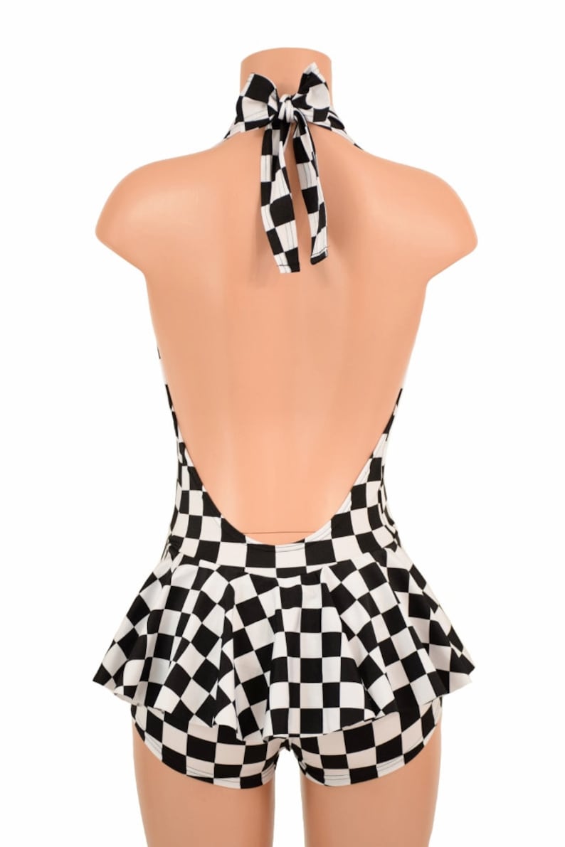 May include: A black and white checkered halter top featuring a deep open back design with a tie closure at the neck and a flared peplum waist detail. The garment displays a consistent grid pattern throughout the bodice and the ruffled hemline.