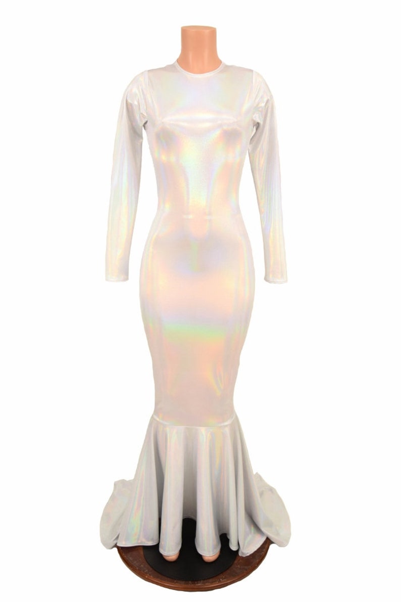 May include: A white iridescent mermaid-style gown with long sleeves and a fitted bodice. The gown has a flowing skirt with a mermaid tail design.
