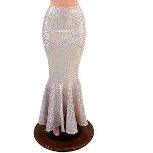 May include: A high-waisted, floor-length skirt featuring a shimmering, iridescent silver finish with a textured scale-like pattern. The garment has a fitted silhouette through the hips and thighs, flaring out into a wide, ruffled mermaid-style hem.