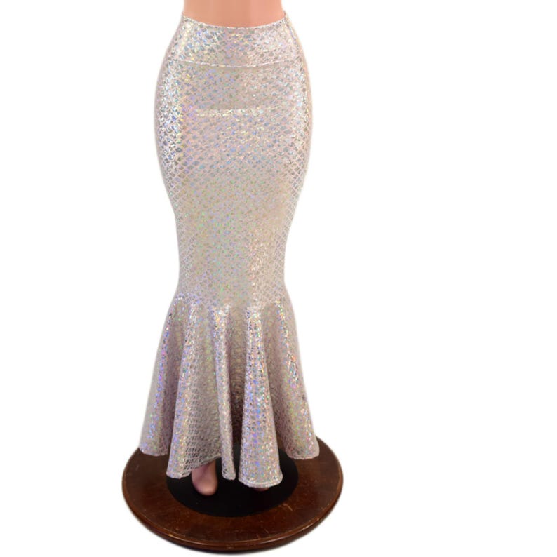 May include: A high-waisted, floor-length skirt featuring a shimmering, iridescent silver finish with a textured scale-like pattern. The garment has a fitted silhouette through the hips and thighs, flaring out into a wide, ruffled mermaid-style hem.