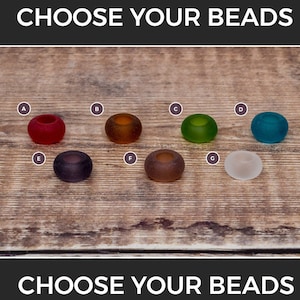 May include: Seven different coloured glass beads, labelled A to G, on a wooden surface. Choose your beads.