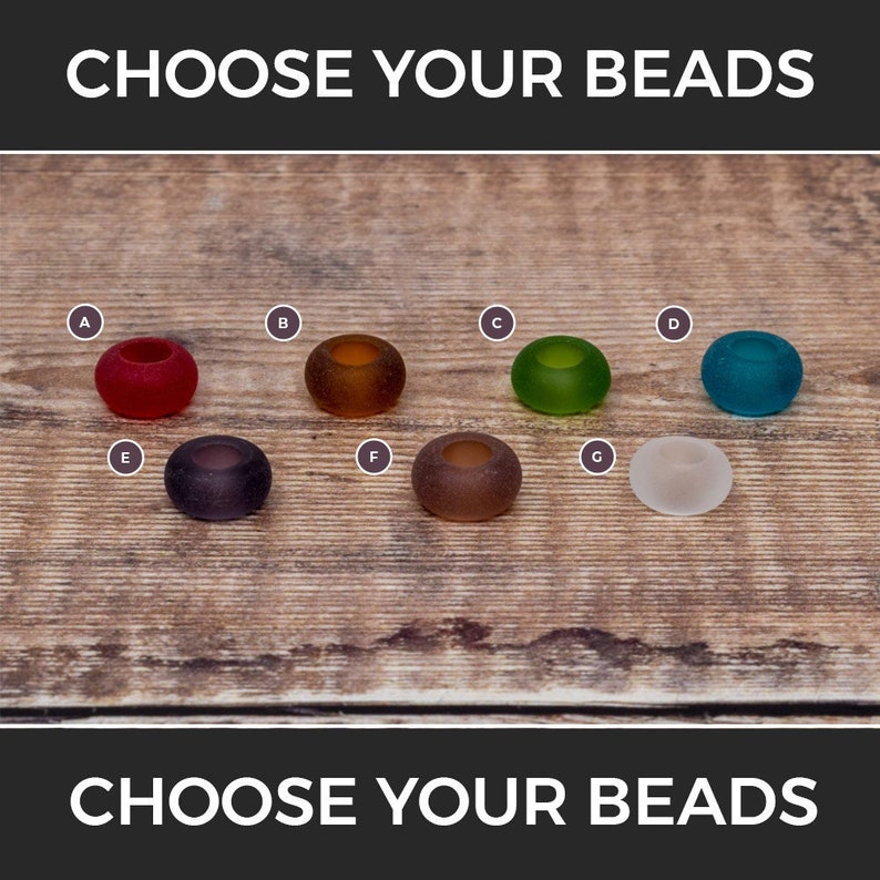 May include: Seven different coloured glass beads, labelled A to G, on a wooden surface. Choose your beads.