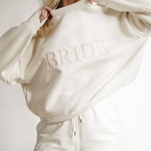 May include: A white sweatshirt and matching shorts with the word "BRIDE" embroidered on both pieces.