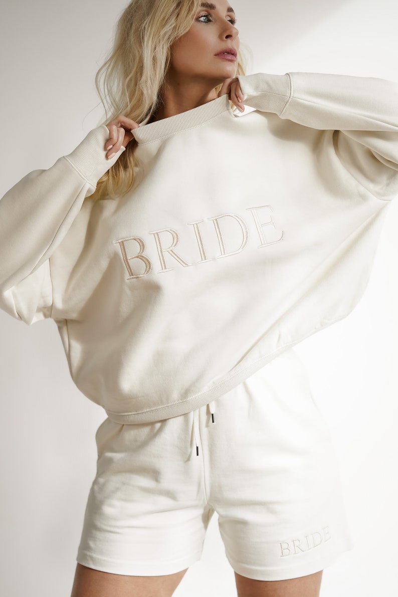 May include: A white sweatshirt and matching shorts with the word "BRIDE" embroidered on both pieces.