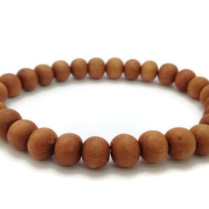 Puede incluir: Un brazalete de cuentas de madera marrón con un acabado liso.