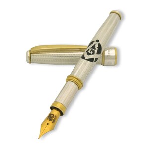 May include: A silver and gold fountain pen with a black and white Masonic symbol on the barrel. The pen has a gold nib and a silver cap.