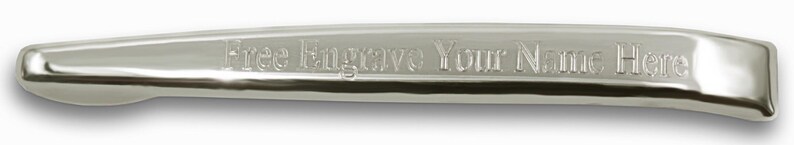 May include: A polished silver-toned metal tie bar with a smooth, reflective surface. The front of the tie bar features the engraved text "Free Engrave Your Name Here" in a clear, sans-serif font, centered along the length of the accessory.