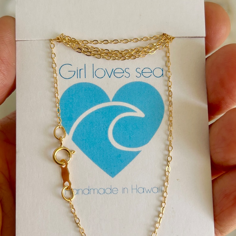 May include: A gold chain necklace with a lobster clasp. The necklace is on a white card with the text "Girl loves sea" and "Handmade in Hawaii".